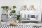 Checkered armchair, wooden mountain decorations and plants in a white, natural bedroom interior for a teenager