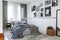 Checkered curtains on the window of contemporary bedroom interior with wooden nightstand and king size bed with grey bedding