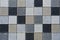 Checkered mosaic, multicolored paving slabs in closeup in gray and beige tones.