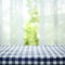 Checkered tablecloth texture top on blur of curtain with window view green from tree garden background