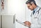 Checking up on his patients progress. a focussed doctor reading a patient file while standing in his consultation room.