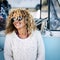 Cheeful and beautiful curly blonde caucasian adult young woman smiling and laughing with sunglasses and blue vintage van in