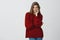 Cheeky and flirty attractive girlfriend in stylish red winter loose sweater smiling tricky and sensually from