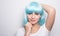 Cheeky young girl in modern futuristic style with blue wig posing over white