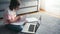 Cheerful 8 years old girl in glasses drawing in a workbook in front of a laptop.