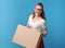 Cheerful active hipster with cardboard box on blue