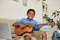 Cheerful adolescent boy playing guitar