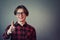 Cheerful adolescent guy showing thumb up, positive gesture, great feedback and approval, wearing eyeglasses looking to camera with