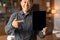 Cheerful adult chinese guy show finger at tablet with empty screen in office interior, cropped