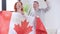 Cheerful adult couple holding Canadian flag talking looking at camera. Positive redhead woman and brunette man posing