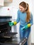 Cheerful adult girl in gloves removing snuff in oven