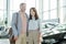 Cheerful affectionate middle aged couple inside large contemporary auto center