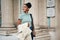 Cheerful African Amerian student girl with trench coat in hand joyfully looking aside on street