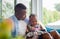 Cheerful african american father looking daughter playing in living room, Cute little girl sitting on the sofa and playing on