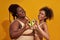 Cheerful african american female models in underwear smiling at camera, making heart love sign with avocado halves