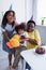 cheerful african american girl holding soft toy while mom and granny hugging her near birthday cake,stock image