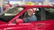Cheerful African American male taxi driver in Christmas Santa hat sitting in the car and dancing, listen music. New Year