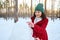 Cheerful African American woman making a snowman in a snow covered woodland. Beautiful sunbeams falling on the snowy forest path.