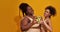 Cheerful african american women in underwear smiling at camera, making heart love sign with avocado halves, posing