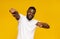 Cheerful african man happily indicating at camera, yellow studio background