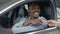 Cheerful african man with keys in hands sitting in new car