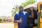 cheerful african man standing next to his tuk tuk taxi smiling and giving a thumbs up