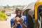 cheerful african man winner holding some money celebrating and jubilant standing next to an auto rickshaw taxi outdoor