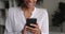 Cheerful African woman standing indoor using smartphone closeup cropped view