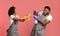 Cheerful Afro Couple Playing With Spray Detergents, Playfully Aiming At Each Other