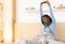 Cheerful Afro Lady Stretching Raising Arms Sitting In Bed