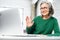 Cheerful aged woman with headset greeting by video