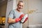 Cheerful aging man using wet cloth to clean his vase