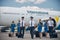 Cheerful aircrew with travel suitcases walking down the airfield