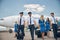 Cheerful airline workers with travel suitcases walking down the airfield