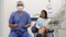 Cheerful american male dentist sitting near medical chair in dental clinic office