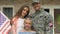 Cheerful american soldier young wife and daughter smiling camera outside house