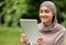 Cheerful arab girl using digital tablet at public park