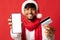 Cheerful arabic man with smartphone and credit card celebrating xmas