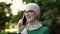 Cheerful arabic woman in hijab using smart phone outdoor walking in park.