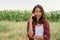 Cheerful asian female farmer and entrepreneur posing in the corn crop and smiling using mobile phone or smartphone app, at camera