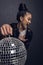 Cheerful asian girl with come here gesture holding disco ball in studio