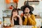 A cheerful Asian girl in a Halloween costume enjoys eating doughnuts with her mom in the kitchen