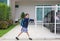 Cheerful asian little child girl in kindergarten uniform trying push and pull door fence of house to close or open before leave