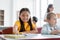 cheerful asian schoolgirl reaching book while