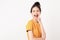 Cheerful Asian woman standing and announcing with hands to the mouth and telling a secret in wearing a yellow shirt.