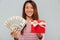 Cheerful asian woman in sweater presenting money and gift