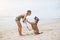 Cheerful asian young woman in eyeglases playing with her dog on the beach