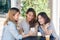 Cheerful asian young women sitting in cafe drinking coffee with friends and talking together.