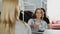 Cheerful attractive girl standing at cashier`s desk, chatting with saleswoman and paying for purchases. Shop assistant