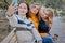 Cheerful attractive three young women best friends having fun and make selfie together outside.